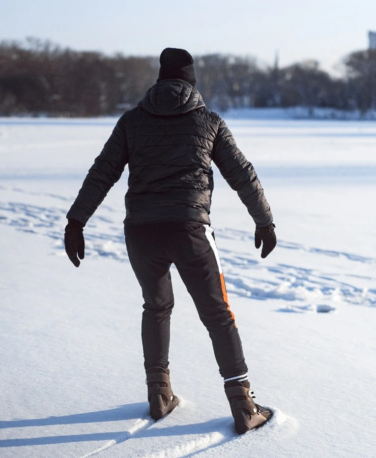 Na zdjęciu widać mężczyznę który ślizga się na zasypanej śniegiem tafli jesiora i nie mysli o sprawie odszkodowania za poślizgnięcie potknięcie.