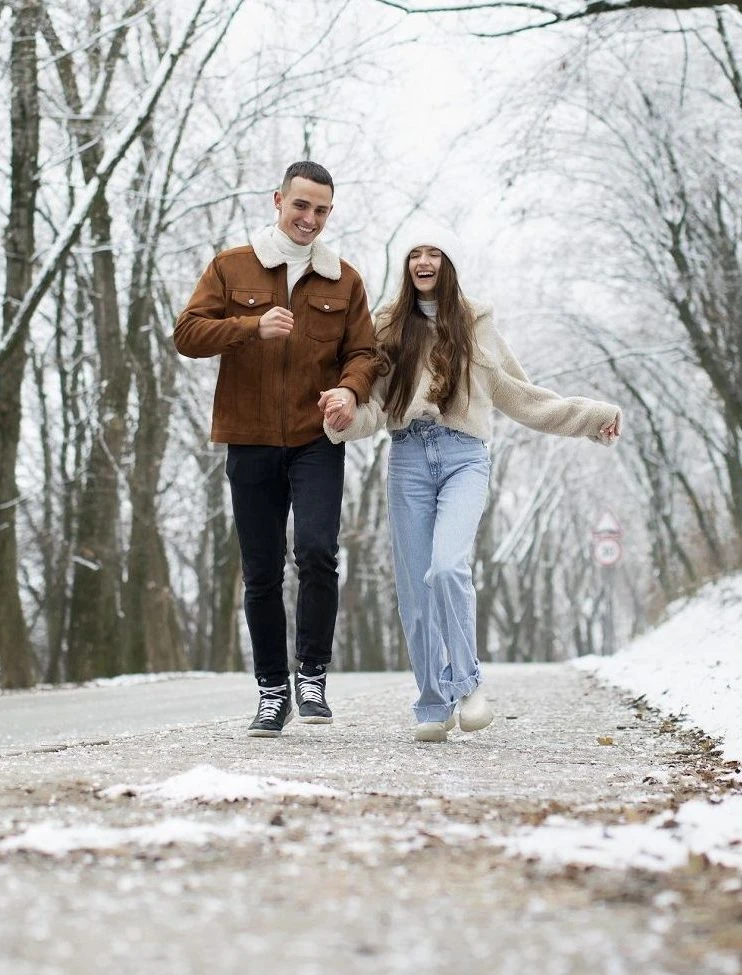 na zdjęciu widać parę nastolatków idącą zimą przez park i smiejących się z odszkodowania za poslizgnięcie potkniecie
